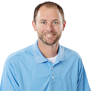 A smiling man with a scruffy beard and a light blue collared shirt