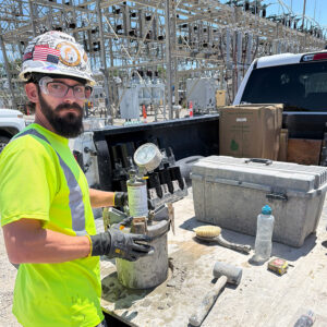 A construction worker in a hard hat holds a bucket with a gauge on top
