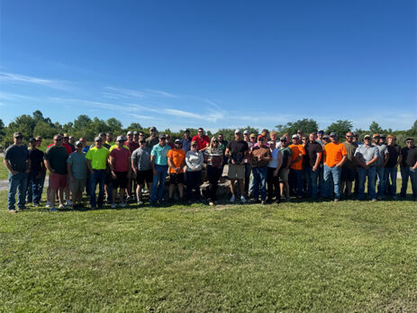 A large group of men and women stand outside
